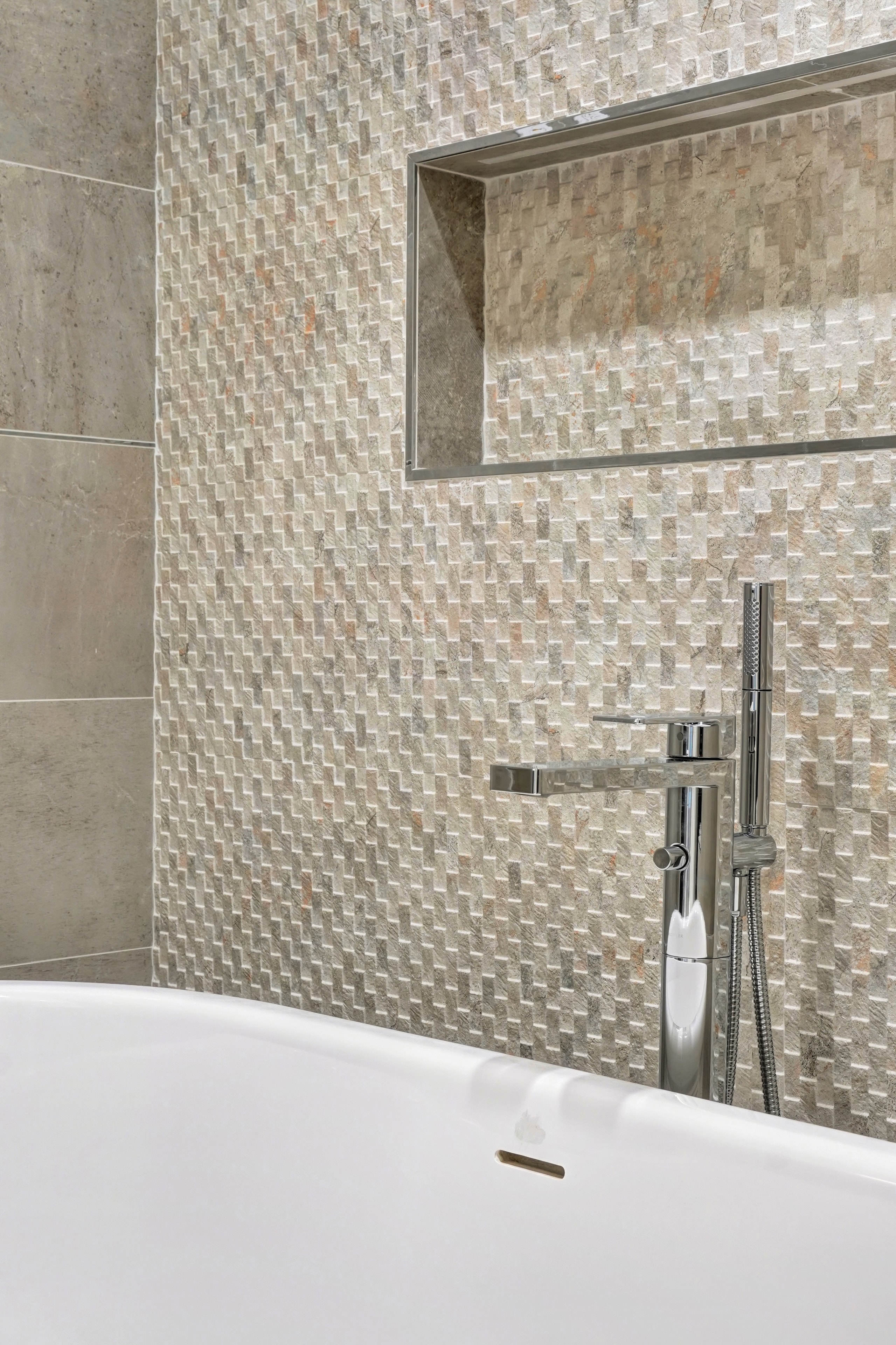 Bathroom remodel in Orange County CA — walk-in shower interior with large-format taupe concrete-look tile walls, mosaic penny tile floor, built-in niche shelf, chrome rain showerhead with slide bar, and tiled bench by Main Street Kitchen & Flooring