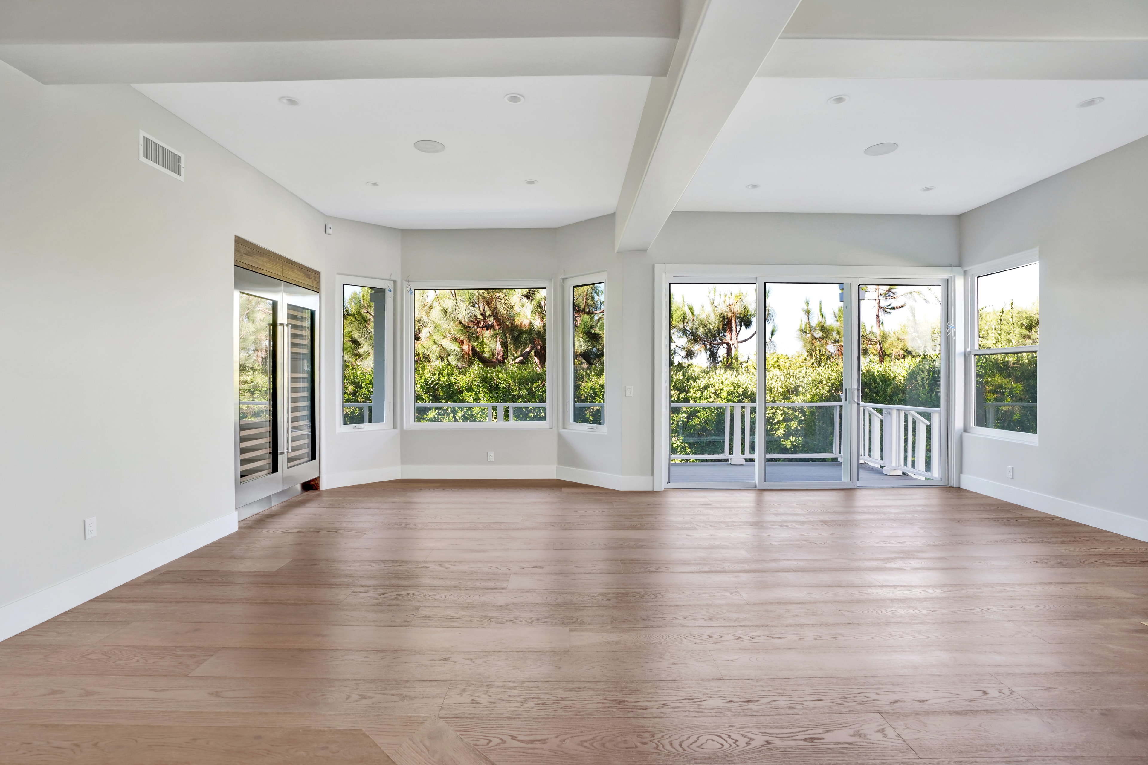 Home remodel in Orange County CA — bright master suite with wide-plank hardwood flooring, coffered ceiling, panoramic windows, and French doors opening to garden balcony by Main Street Kitchen & Flooring