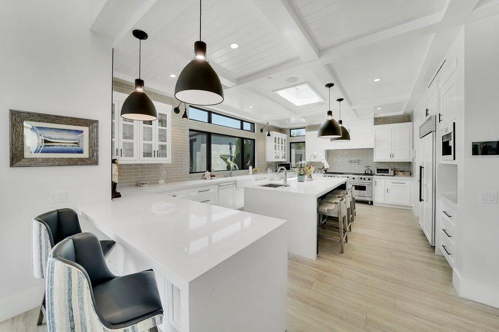 Kitchen remodel in Irvine CA — white shaker cabinets, quartz countertops, black pendant lights, and light hardwood flooring by Main Street Kitchen & Flooring