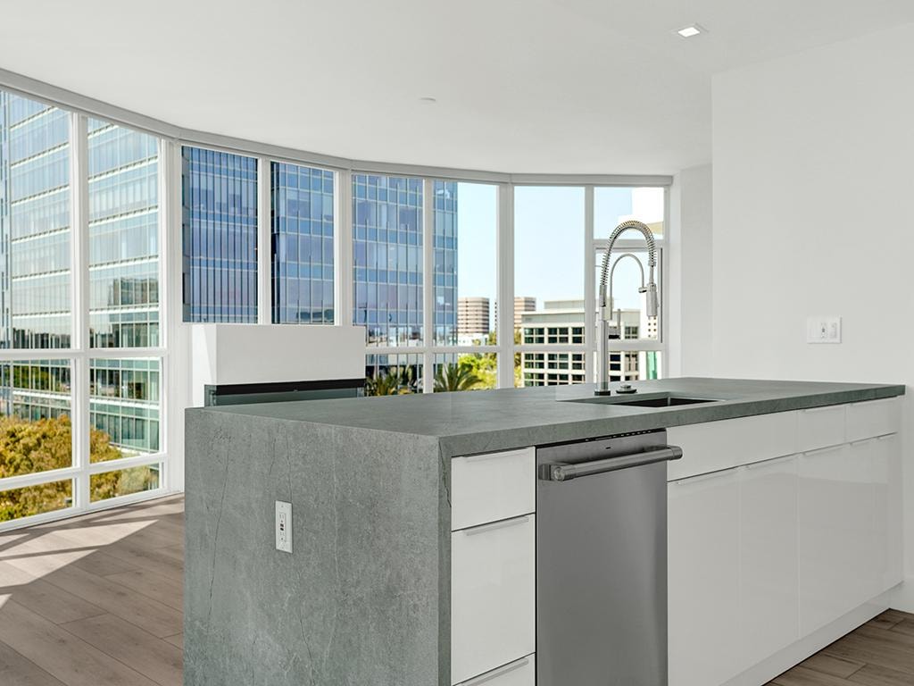 Open-concept kitchen remodel in Irvine CA — blue shaker island, white cabinets, skylights, and black pendant lights by Main Street Kitchen & Flooring
